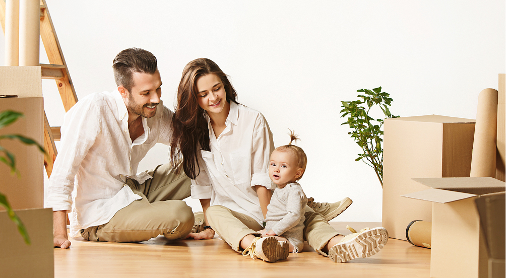 Молодая семья с ребёнком среди коробок в новой квартире — использование материнского капитала на улучшение жилищных условий