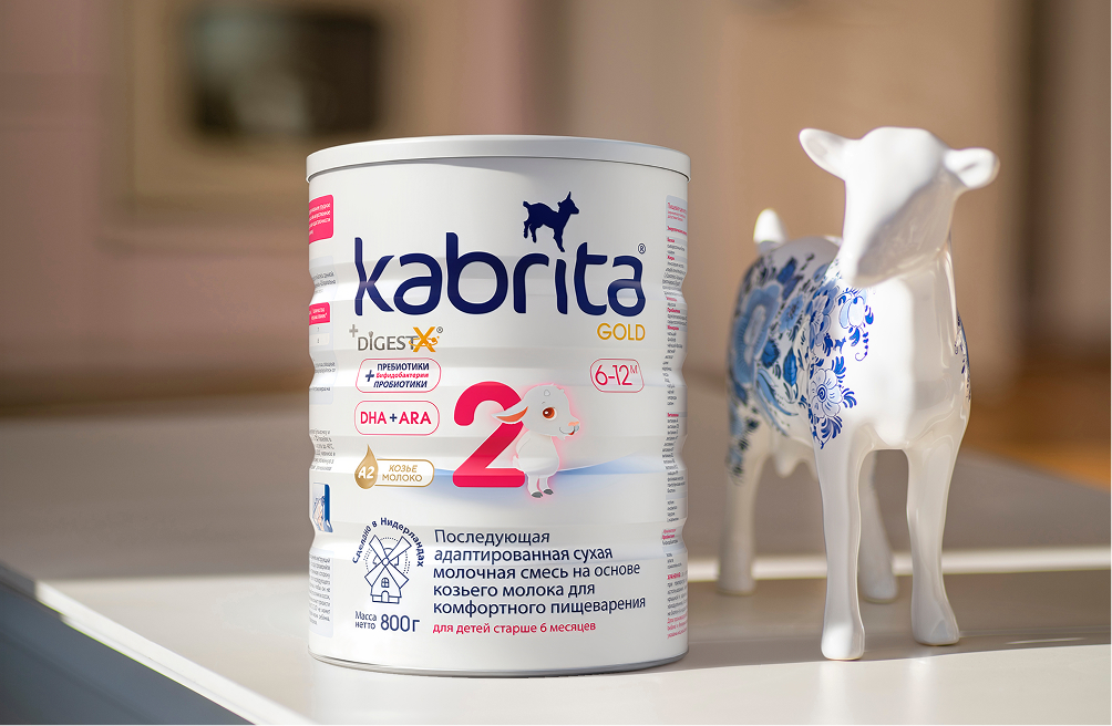 Мама отмеряет мерной ложкой смесь Kabrita Gold 2 над открытой банкой на кухонной столешнице — правильное приготовление адаптированной смеси сохраняет все питательные компоненты
